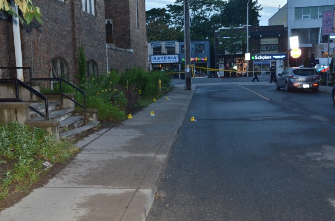 The west sidewalk of Bowden Street across the street from 7Numbers restaurant. Yellow evidence markers indicate the locations of the five brass cartridge cases that were found.