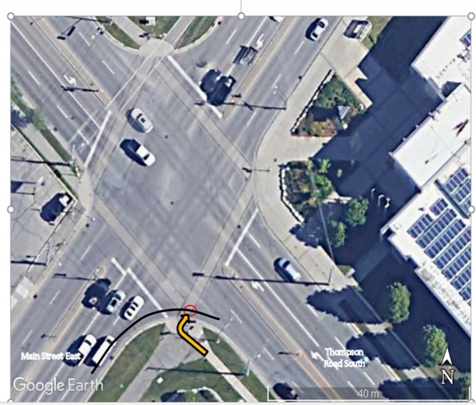 Figure 1 - Cette photographie est une représentation Google Earth® des lieux. La ligne noire et la flèche orange ont été ajoutées pour montrer la trajectoire du véhicule de l’AI et celle de la plaignante, respectivement. Le cercle rouge représente la zone d’impact.