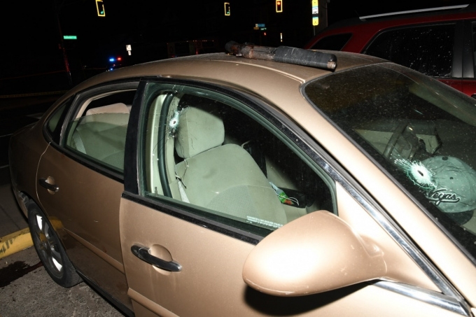 Figure 2 – Le véhicule Buick Allure 2005 à quatre portes. Des trous de balle sont visibles dans le pare-brise et la vitre du côté passager. Le fusil à canon tronqué se trouve sur le véhicule.