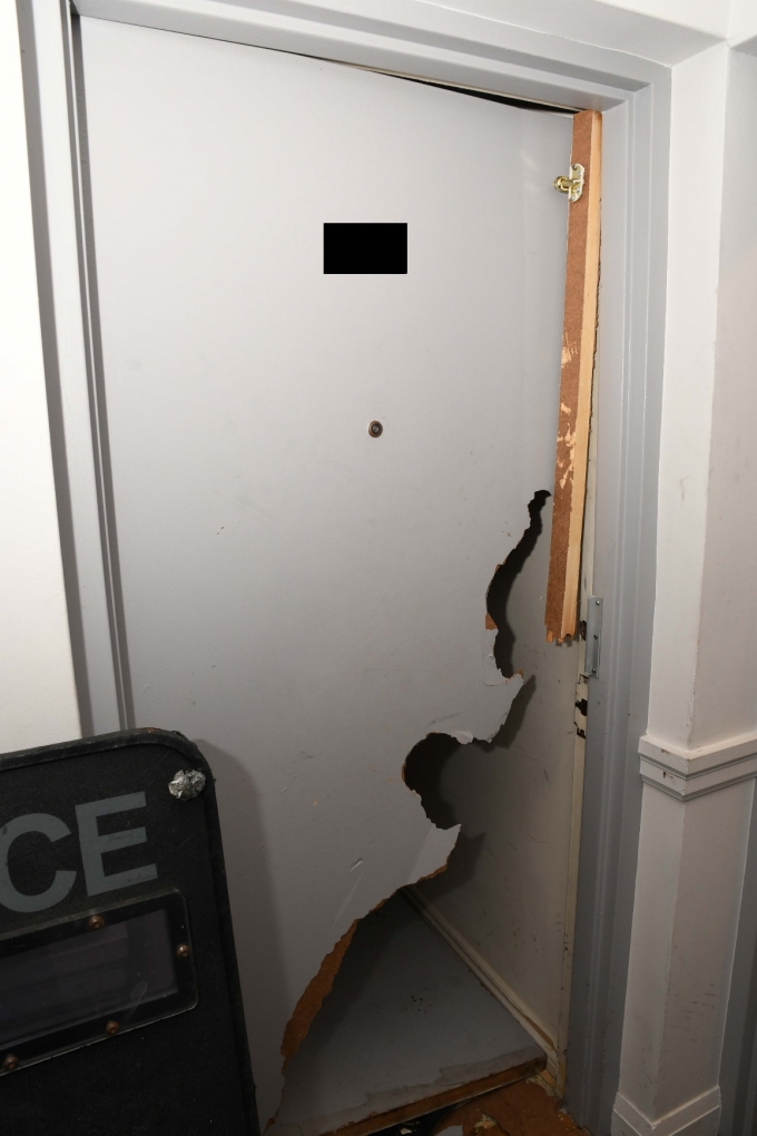 Figure 2 – La porte brisée du logement et le bouclier pare-balles de la police.