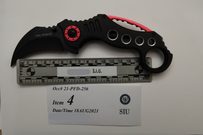 Photograph of knife on table over 15 centimeter ruler with an identification SIU identification card.