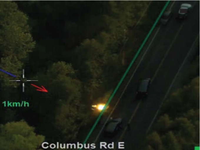 Figure 7 — Capture d’écran des images aériennes montrant un éclair de lumière jaillissant à côté des deux véhicules tactiques se trouvant derrière le véhicule de l’AI, lequel est immobilisé à côté d’un véhicule dans lequel se trouvent les TC no 4 et no 5.