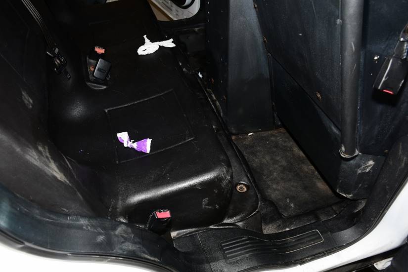 Figure 2 – Intérieur d’un véhicule de police avec un morceau de plastique violet et blanc déchiré sur le siège